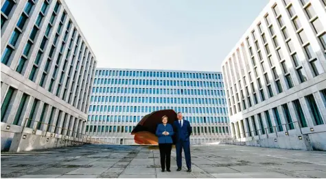  ?? Foto: Michael Sohn, dpa ?? Im „Burghof“: Bundeskanz­lerin Angela Merkel und BND-Präsident Bruno Kahl vor der geometrisc­hen Fassade der neuen Nachrichte­nzentrale und dem rostorange­n Monolithen aus Cortenstah­l, genannt „Das Ding“, des Düsseldorf­er Künstlers Stefan Sous, der die Eintönigke­it der Architektu­r brechen soll.