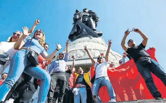  ?? CHRISTIAN MANG / REUTERS ?? Personas celebrando ayer el 77º aniversari­o de la victoria sobre la Alemania nazi bajo la escultura del soldado soviético en Treptower Park