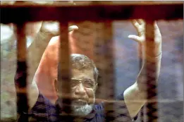  ??  ?? Former Egyptian President Mohamed Mursi reacts behind bars with other Muslim Brotherhoo­d members at a court in the outskirts of Cairo. Reuters