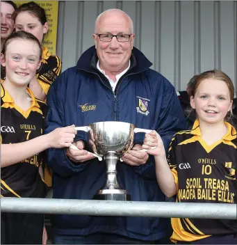  ??  ?? Kevin Waters, Vice-President of the Rackard League, presents the cup to Kilrush joint captains Eimear Byrne and Tara Kenny.