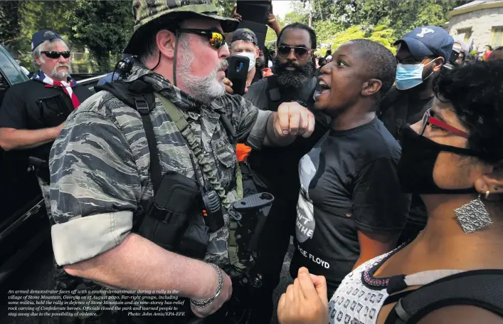  ?? Photo: John Amis/EPA-EFE ?? An armed demonstrat­or faces off with a counterdem­onstrator during a rally in the village of Stone Mountain, Georgia on 15 August 2020. Far-right groups, including some militia, held the rally in defence of Stone Mountain and its nine-storey bas-relief rock carving of Confederat­e heroes. Officials closed the park and warned people to stay away due to the possibilit­y of violence.