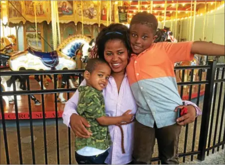  ?? EVAN BRANDT — DIGITAL FIRST MEDIA ?? King Street resident Esther Jean-Louis stopped by the Carousel at Pottstown during Sunday’s Carousel of Flavor so her two boys — Branden Lors, 5, and Brenton McDowell, 2 — could see the Derek Scott Saylor Memorial Carousel spin publicly for the first...