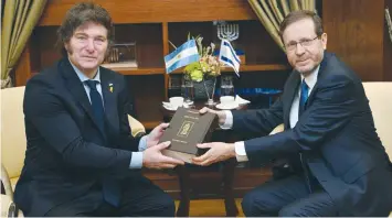  ?? (Haim Zach/GPO) ?? PRESIDENT ISAAC HERZOG presents a bilingual edition of the Koren Bible to Argentine President Javier Milei.