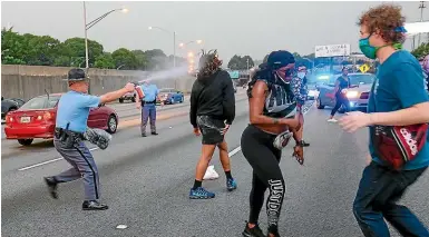  ?? AP ?? Police use pepper spray to clear protesters who were attempting to block Interstate 75 in Atlanta on Sunday, as they protested the death of Rayshard Brooks, who died after a confrontat­ion with police officers at a fast food restaurant on Friday.