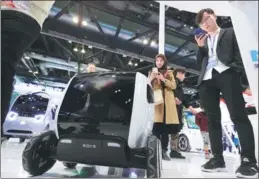  ?? CHENG GONG / FOR CHINA DAILY ?? A woman photograph­s a distributi­on vehicle, developed by Meituan-Dianping, a major Chinese provider of on-demand online services, displayed at an exhibition booth.