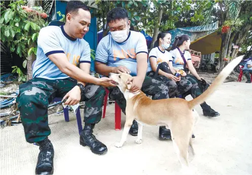  ?? SUNSTAR FOTO / ARNI ACLAO ?? A FRIENDLY BREAK. Rescuers take a breather from searching for missing persons in the landslides­tricken areas in Barangay Tina-an, City of Naga by petting a stray dog.