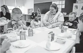  ?? MATT ROURKE/AP ?? Teacher Patty Cronin helps 3-year-old Makayla Grant open her package of cereal during preschool in Philadelph­ia on Friday.