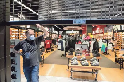  ??  ?? Sales manager Shawn Densmore holds the gate at Foot Locker inside Oak Court Mall, where they are limiting the store to 50% capacity on its second day after reopening Tuesday.