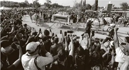  ?? Jason Fochtman / Staff photograph­er ?? People gather as the horse-drawn carriage carrying the body of George Floyd enters Houston Memorial Gardens in June.