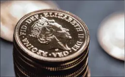  ??  ?? Sovereign gold bullion coins sit on display at The Royal Mint in Llantrisan­t, Wales. Britain’s Royal Mint is making 1.5 billion new one-pound coins, which will enter circulatio­n today.