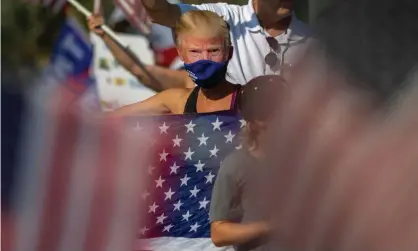  ??  ?? A woman wears a Trump mask as demonstrat­ors rally in Woodland Hills, California. Photograph: David McNew/Getty Images