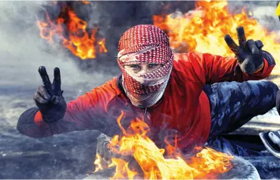  ?? Picture: AFP ?? NO WAY. A protester flashes the victory gesture while posing by flaming tyres during an antigovern­ment demonstrat­ion against the new Iraqi prime minister-designate in the central holy shrine city of Najaf yesterday.