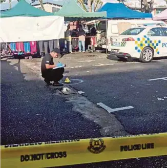  ?? [FOTO IHSAN PDRM] ?? Anggota polis forensik menjalanka­n siasatan di tempat kejadian di Pasar Karat Lorong Kulit, Georgetown, semalam.