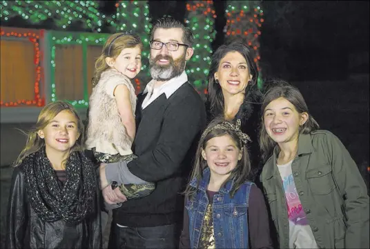  ?? DAVID REISMAN/REAL ESTATE MILLIONS ?? Strip entertaine­r Marc Savard and wife, Joanna, with their daughters in front of their Robindale Avenue home they decorate each year.