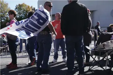  ??  ?? A man wears a Trump flag on his back as he waits in line for a Make America Great Again campaign rally held by Trump at the McKenzie Arena in Chattanoog­a, Tennessee. — AFP photo