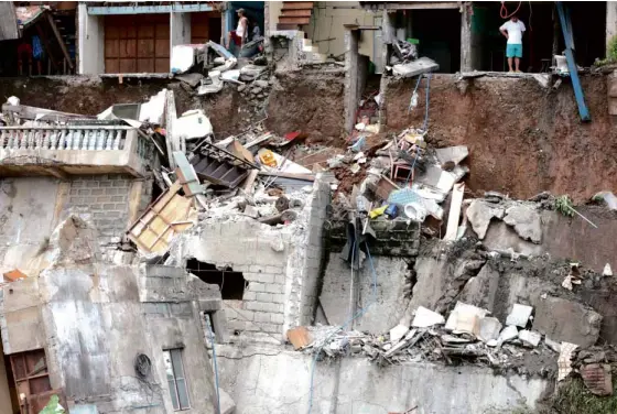  ?? GRIG C. MONTEGRAND­E ?? RESIDENTS examine the damage to their houses along the Nangka River in Marikina City after strong currents and heavy rains in the past few days softened the riverbank, leading to the collapse of a portion of the dike.