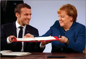  ?? REUTERS ?? French President Emmanuel Macron and German Chancellor Angela Merkel sign a new agreement on bilateral cooperatio­n and integratio­n, known as Treaty of Aachen, in Aachen, Germany, on 22 January.