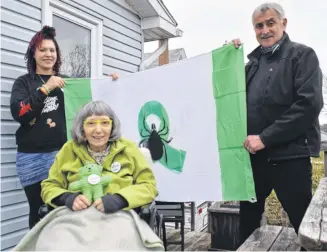  ?? ADAM MACINNIS ?? Janelle Clyke, left, and John Ashton hold a flag that was the brainchild of Brenda SterlingGo­odwin, front. Ashton, who is a graphic designer put the design onto paper and then Clyke made the flag. A duplicate is hanging at Halifax City Hall for Lyme Awarness Month.