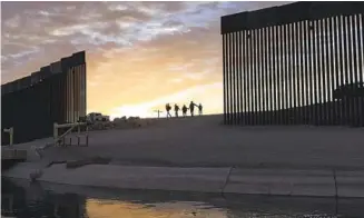  ?? EUGENE GARCIA AP ?? In 2021, two migrant families pass through a gap in the border wall to reach the U.S. in Yuma, Ariz.