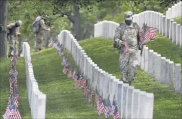  ?? Matt Mcclain / Washington Post ?? Soldiers place flags near headstones at Arlington National Cemetery in advance for Memorial Day on Thursday. Social distancing, closures and restrictio­ns have disrupted the rituals of grief in honor of those who have died.