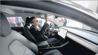  ?? Allen J. Schaben Los Angeles Times ?? JAY CORSON of Sherman Oaks checks out the Model 3 at a showroom in Century City last month. Early versions of the electric sedan have garnered online complaints from some Tesla fans.