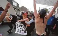  ??  ?? AKTIVIS memakai topeng wajah Marine (kiri) dan Trump (tengah), ditahan ketika melakukan demonstras­i di Henin Beaumont, utara Perancis. - AP