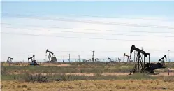  ?? AP Photo/Jeri Clausing, File ?? ■ Oil rigs stand in the Loco Hills field along U.S. Highway 82 in Eddy County, near Artesia, N.M., one of the most active regions of the Permian Basin. Government budgets are booming in New Mexico. The reason behind the spending spree — oil. New Mexico is the No. 2 crude oil producer among U.S. states and the top recipient of U.S. disburseme­nts for fossil fuel production on federal land. But a budget flush with petroleum cash has a side effect: It also puts the spotlight on how difficult it is for New Mexico and other states to turn their rhetoric on tackling climate change into reality.