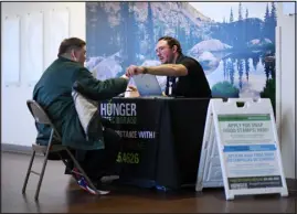  ?? HYOUNG CHANG — THE DENVER POST ?? Brandon Reimers, right, of Hunger Free Colorado helps people with informatio­n for applying for the Supplement­al Nutrition Assistance Program in the lobby of Stride Community Health Center in Wheat Ridge on Dec. 7.
