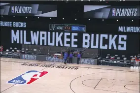  ?? KEVIN C. COX — THE ASSOCIATED PRESS ?? Referees stand on an empty court before the start of a scheduled playoff game between the Bucks and Magic Aug. 26in Lake Buena Vista, Fla.