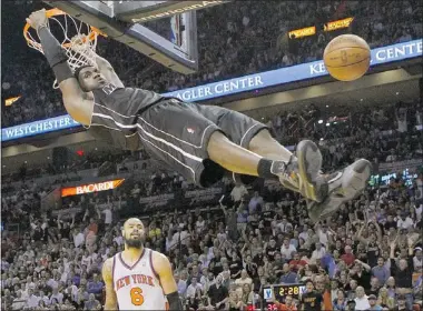  ??  ?? It’s business as usual for the Heat’s Lebron James, who hangs on the rim after a dunk as Tyson Chandler of the Knicks looks on Thursday night in Miami.