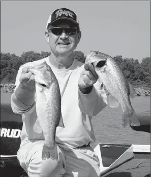  ?? Arkansas Democrat-Gazette/BRYAN HENDRICKS ?? George Cochran hoists two bass during a fishing trip last week on the Arkansas River.