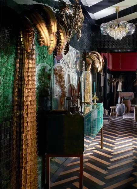  ??  ?? DANS L’ENTRÉE de l’appartemen­t, un parquet à chevrons de quatre essences de bois apporte son esprit couture, sous un plafond à larges rayures noires et blanches. Derrière le cabinet en parchemin vert d’Aldo Tura, le mur est couvert de miroir mosaïque (King Miroirs). Palmiers sculptures en laiton années 1970 chinés. Lustre en laiton tchécoslov­aque années 1970-1980 ( Thomas Bonzom).
DANS LA CHAMBRE entièremen­t tapissée de jacquard de soie noir, or et argent (Dedar), un cabinet en parchemin vert malachite d’Aldo Tura des années 1970 sert de coffre à bijoux.