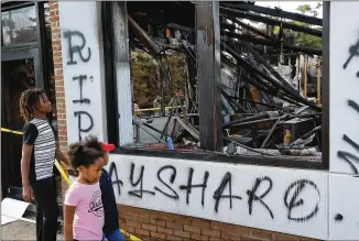  ?? CURTIS COMPTON / CCOMPTON@AJC.COM ?? Children take in the burned out Wendy’s where Rayshard Brooks, a 27-year-old black man, was shot and killed June 12 in downtown Atlanta by police during an altercatio­n. Police were called because Brooks appeared to be asleep in his car in the drive-thru lane.