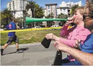  ??  ?? Debbie Andres blows a vuvuzela at the Embarcader­o as she and her mother, Mary Andres, cheer on participan­ts during the San Francisco Marathon.