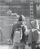  ?? AFP/GETTY IMAGES ?? People in Tokyo look at a stock indicator showing the exchange rate of the Japanese yen against the dollar on Feb. 7.