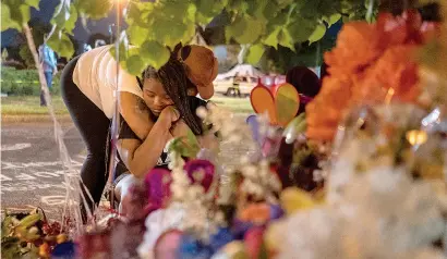  ?? Photo by Libby March
for The Washington
Post ?? ABOVE: Pleazant Davis, 22, is comforted by her friend, Tasha Dixon, 35, at a memorial
honoring the victims of the Tops
shooting across the street from the store in Buffalo on
May 15.