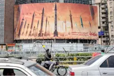  ?? — AFP photos ?? A motorcycle speaks on a phone while driving past a billboard depicting named Iranian ballistic missiles in service, with text in Arabic reading “the honest [person’s] promise” and in Persian “Israel is weaker than a spider’s web”, in Valiasr Square in central Tehran.