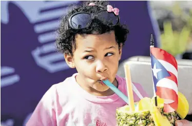  ?? Photos by Melissa Phillip / Staff photograph­er ?? Andrea Morales, 2, takes a sip from a pineapple held by her dad, Robert, as she takes in the sights, sounds and tastes of the 13th annual Puerto Rican and Cuban Festival on Saturday.
