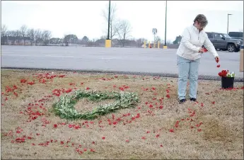  ?? TIMES photograph by Annette Beard ?? Mechel Wall of Wallflower Farms scattered red rose petals around a heart-shaped floral arrangment on the lawn in front of Walmart Neighborho­od Market as a memorial to covid-19 victims on Monday, March 1.