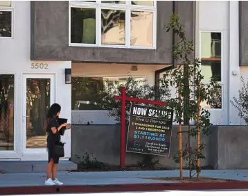  ?? ?? Slumping market: A woman stands near a ‘for sale’ sign displayed outside a townhouse style building in Los Angeles. The US housing market is seeing a slowdown in home sales
due to the Fed raising mortgage interest rates to help fight inflation. — AFP