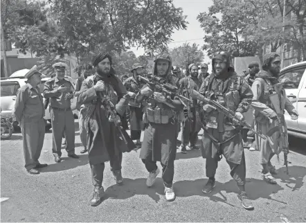  ?? GUL/AP RAHMAT ?? Taliban fighters patrol in Kabul, Afghanista­n, on Thursday. The two uniformed men at left are traffic officers.