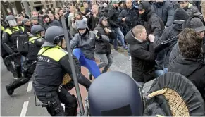  ??  ?? Crowd control: Dutch riot police wielding their batons as they disperse a group of people during pro and anti immigratio­ns rallies in Amsterdam, netherland­s.