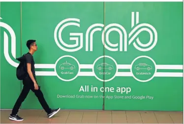  ??  ?? Strong presence: A man walks past a Grab office in Singapore. Grab is one of the few SouthEast Asian apps that enjoy a wide geographic­al footprint.