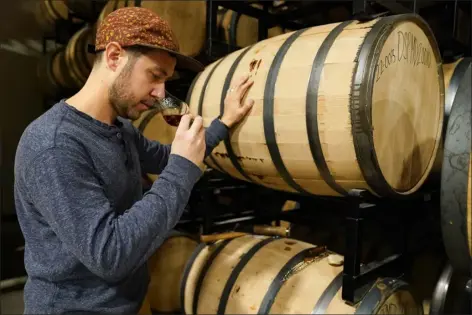  ?? JULIO CORTEZ — THE ASSOCIATED PRESS ?? Eli Breitburg-smith, head distiller and co-owner of Baltimore Spirits Company, checks the quality of rye whiskey from a barrel on Wednesday. Spirits have surpassed beer for U.S. market share supremacy, led by a resurgent cocktail culture — including the popularity of ready-to-drink concoction­s, according to a spirits industry group.