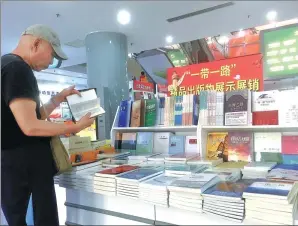  ?? PROVIDED TO CHINA DAILY ?? A reader flips through new books on the Belt and Road Initiative at a Beijing bookstore.
