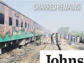  ?? Picture: Reuters ?? People gather where a fire broke out in a passenger train near Rahim Yar Khan in Pakistan on Thursday.