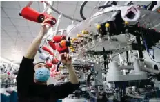  ?? — Reuters ?? An employee wearing a face mask works on a production line manufactur­ing socks for export at a factory in Huzhou’s Deqing county, Zhejiang, China.