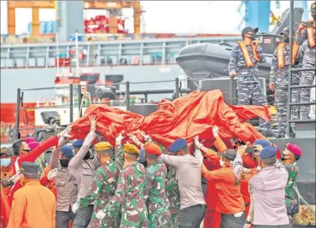  ?? AFP ?? Rescue workers carry recovered debris at the port in Jakarta on Sunday during the search operation for Sriwijaya Air flight SJY182 which crashed after take-off.