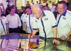  ??  ?? For the people: Najib signing the official opening plaque during the Residensi Pandanmas handing over ceremony as Tan (right) and Federal Territorie­s Minister Datuk Seri Tengku Adnan Tengku Mansor (third from right) look on.