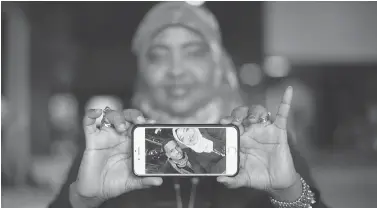  ?? JONATHAN HAYWARD / THE CANADIAN PRESS ?? Saciido Shaie shows a picture of herself and friend Mohamed Badal at a Somali restaurant in Minneapoli­s, Minn. Badal left the U.S. last week to attempt entry into Canada and didn’t tell his friends of his plans.